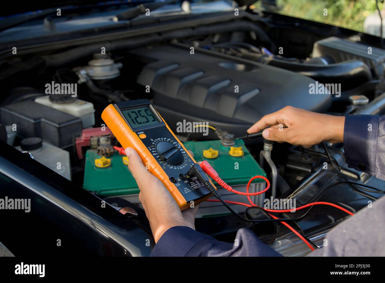 Auto meccanico con un multimetro voltmetro auto controllo di tensione della  batteria in corrispondenza di officina Foto stock - Alamy