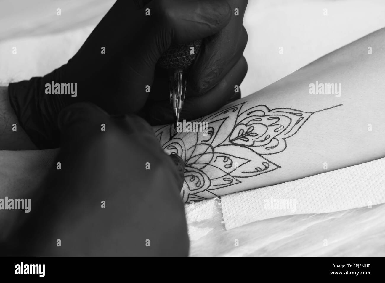 Artista professionista che fa tatuaggio a portata di mano a tavola, primo piano. Fotografia in bianco e nero Foto Stock