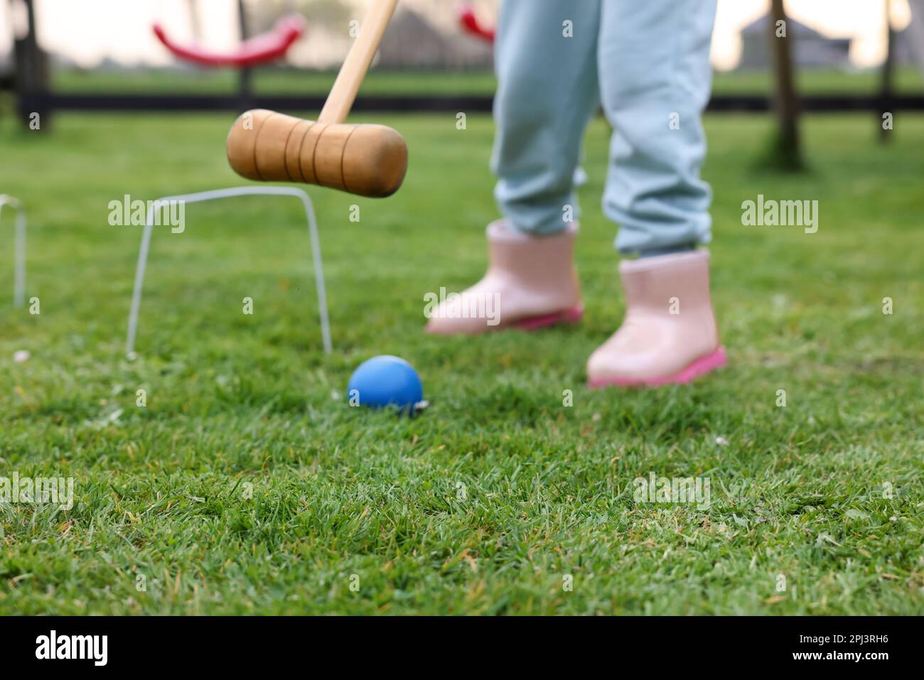 Ragazza che gioca croquet su erba verde all'aperto, primo piano Foto Stock