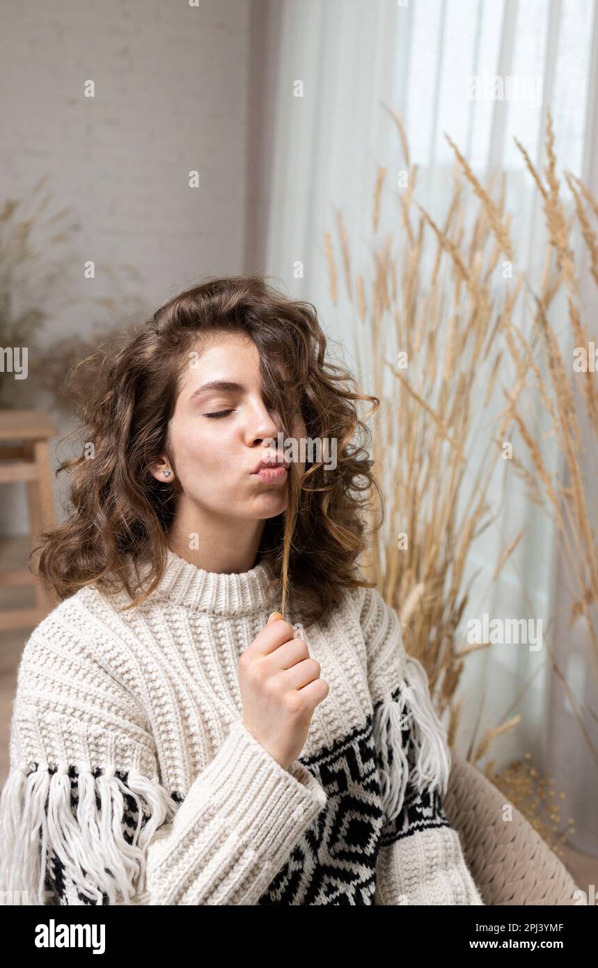 foto di un'attraente ragazza adolescente, una giovane donna dai capelli ricci, vestita con un caldo maglione, labbra ripiegate a forma di bacio d'aria. misterioso, dre Foto Stock
