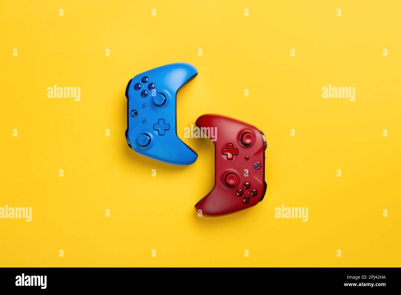 Due gamepad wireless a marchio xbox rosso e blu si trovano su uno sfondo giallo di nuovo a retro. Gioco di squadra, molto spazio Foto Stock