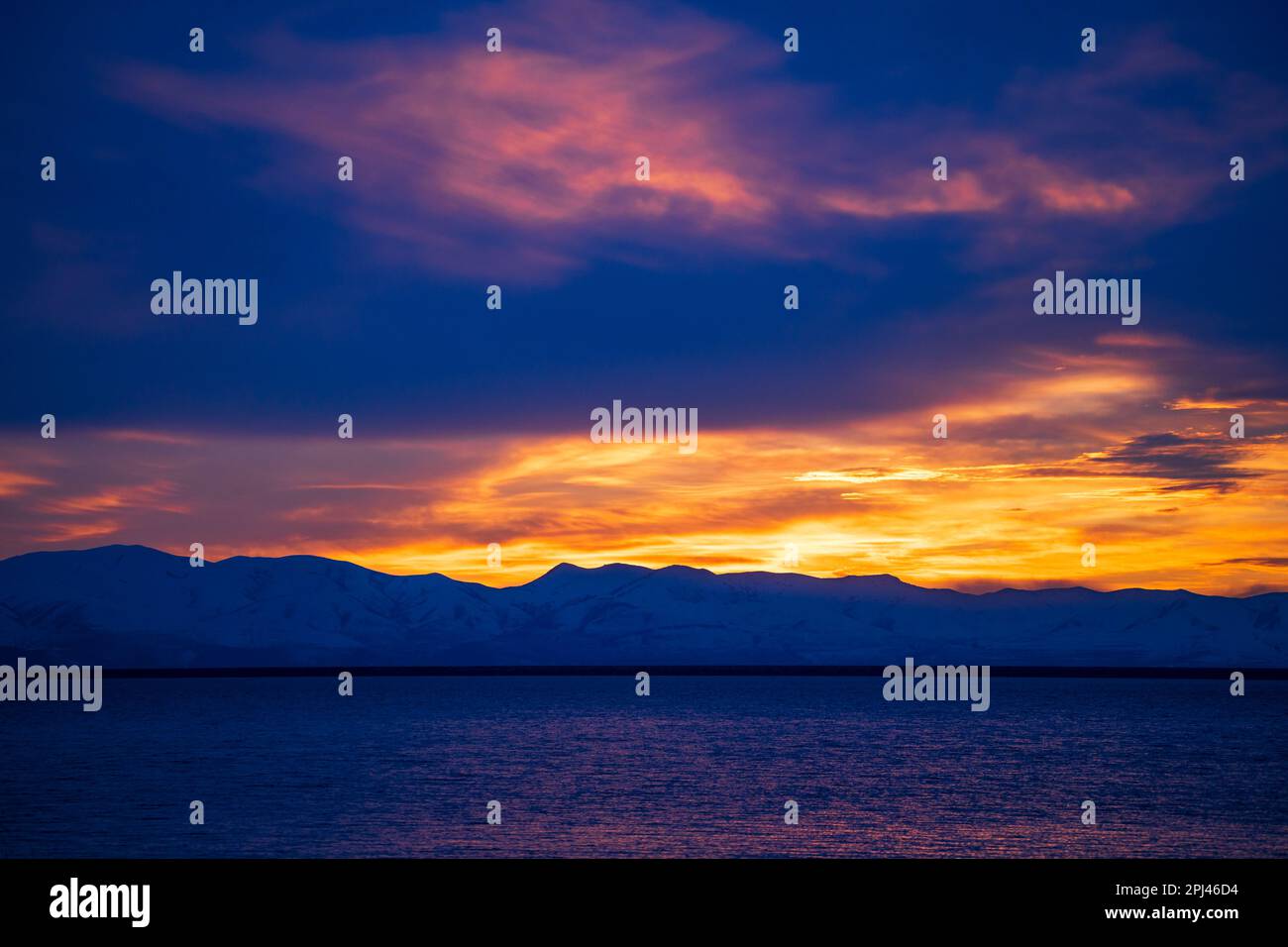 Il sole tramonta sulle montagne innevate del promontorio e si riflette sulle acque del lago artificiale di Willard Bay, Willard, Box Elder County, Utah, USA. Foto Stock