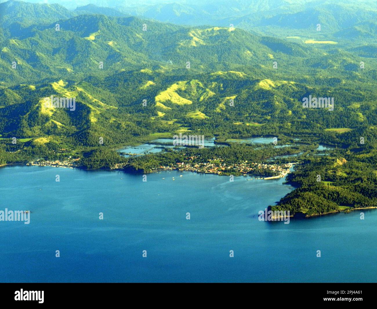 Arcipelago filippino: Vista aerea di una città costiera, sostenuta da gamme di colline boscose. Foto Stock