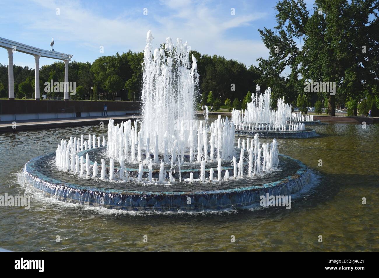 Uzbekistan, Tashkent: Piscina con tre fontane, con parte dell'Arco dell'Indipendenza sulla sinistra, a Mustaqillik Maydoni. Foto Stock