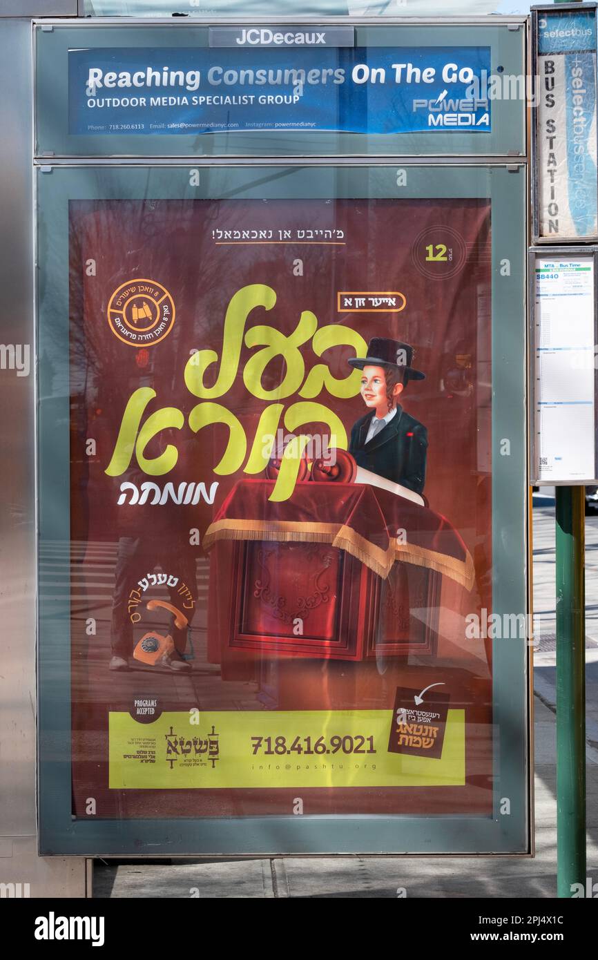Un segno Yiddish su un chiosco di autobus che fa pubblicità a una scuola che insegna il difficile compito di leggere ad alta voce dalla Torah. A Brooklyn, New York. Foto Stock