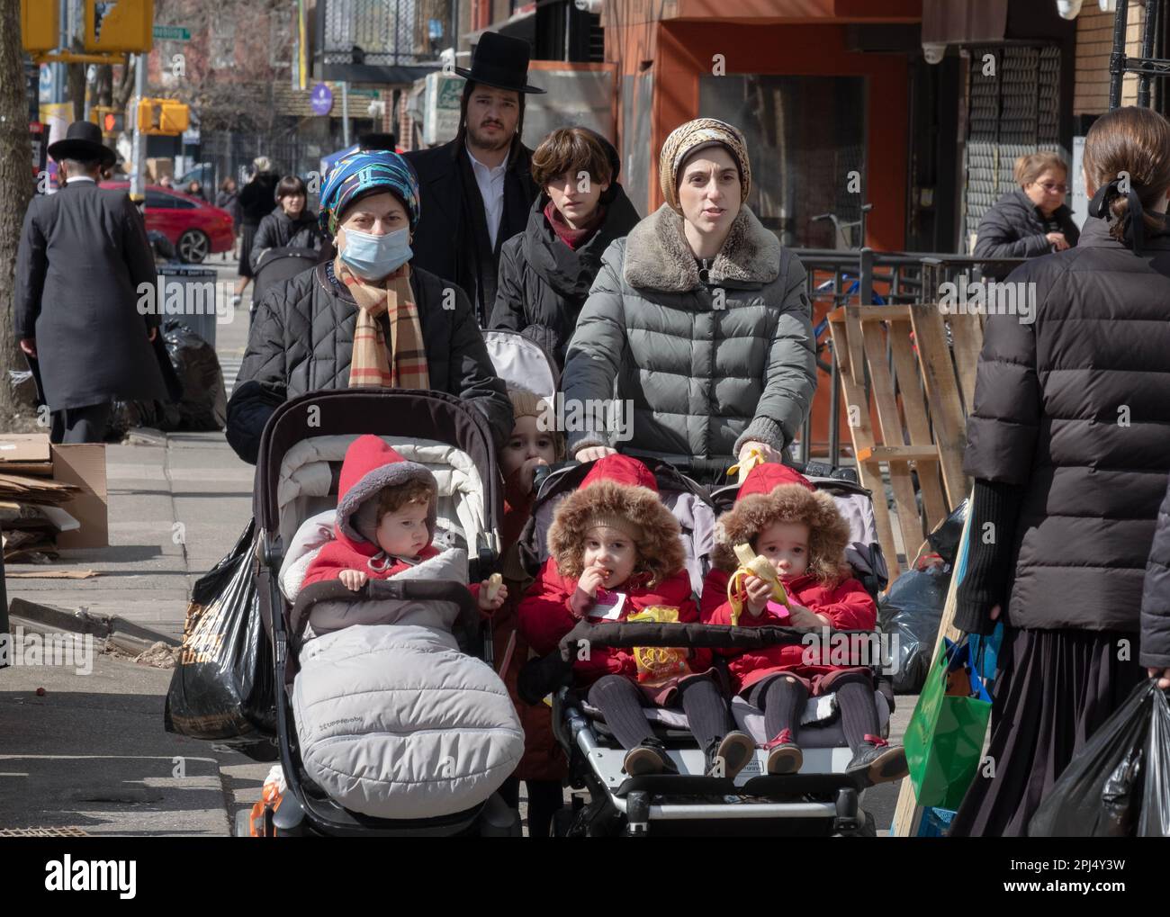 Le madri e i bambini ortodossi ebrei indossano cappotti invernali rossi. A Brooklyn, New York. Foto Stock