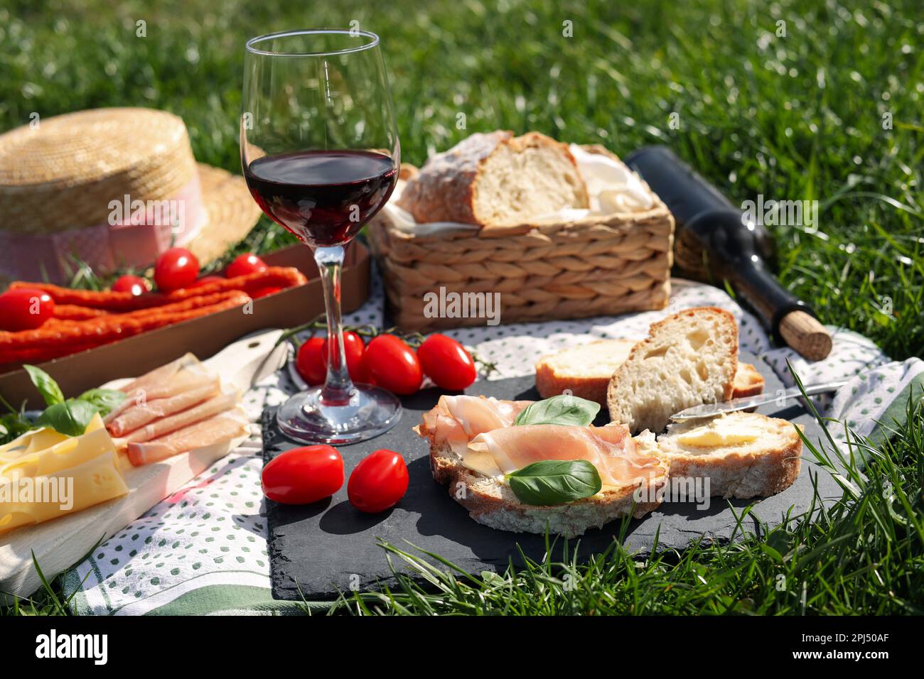 Coperta con vino e spuntini per picnic su erba verde Foto Stock