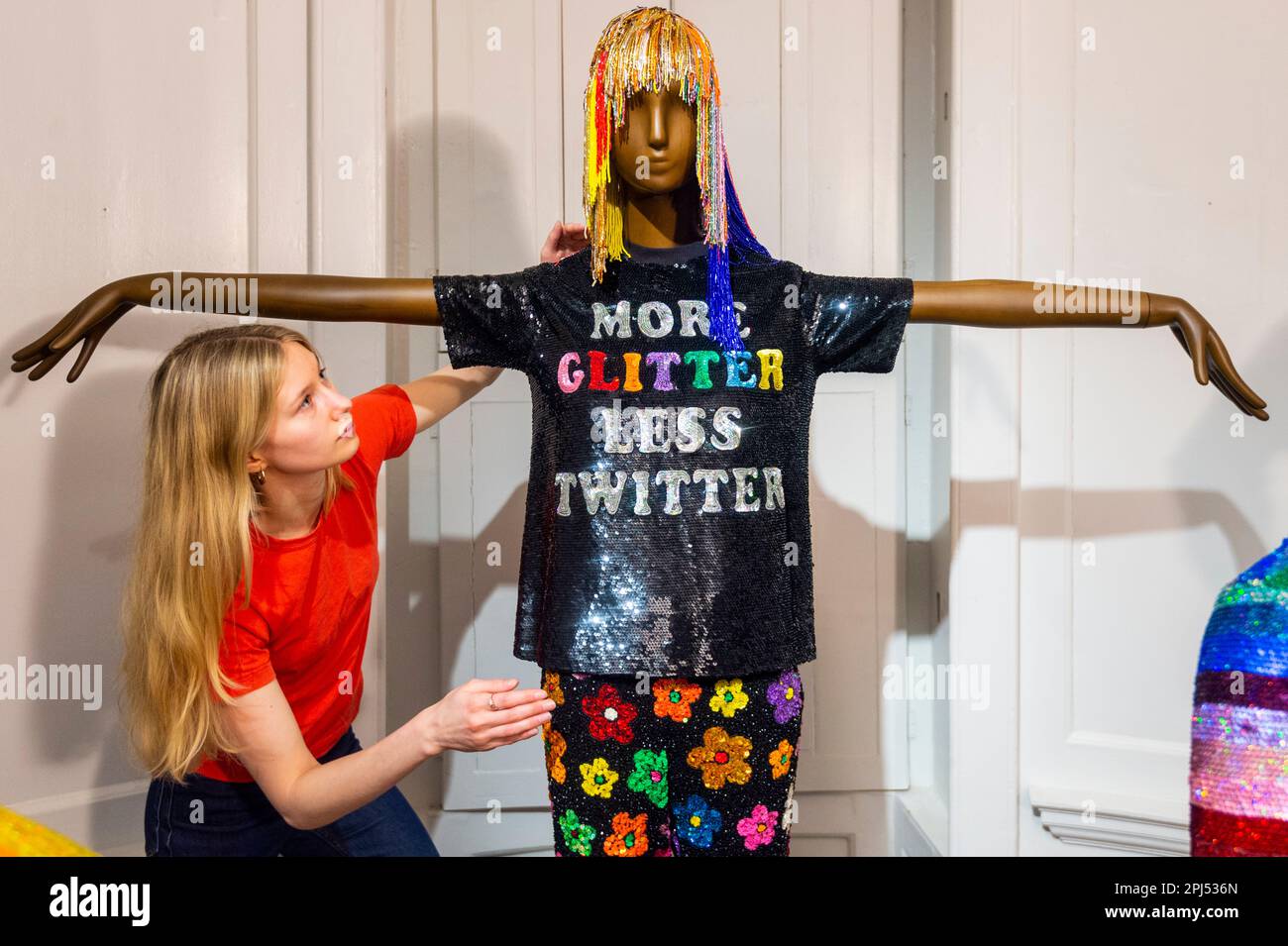 Londra, Regno Unito. 31 marzo 2023. Un membro dello staff con 'più glitterless Twitter t-shirt', AW2017 e 'pantaloni floreali', AW2020, in un'anteprima 'Ashish: Fall in Love and Be More Tender', il primo grande sondaggio di opere del fashion designer Ashish. Oltre 60 progetti degli ultimi 20 anni, tra cui alcuni indossati da celebrità globali, sono in mostra alla William Morris Gallery, Walthamstow, 1 aprile – 10 settembre 2023. Credit: Stephen Chung / Alamy Live News Foto Stock