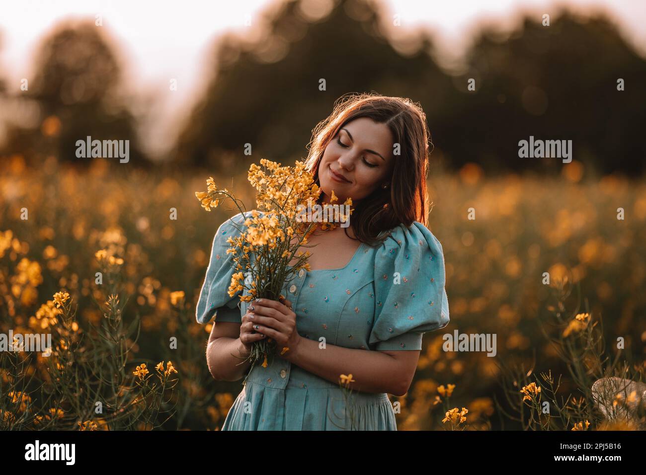 Donna felice in fioritura canola fiori campo. Donna in abito retrò, stagione primaverile Foto Stock