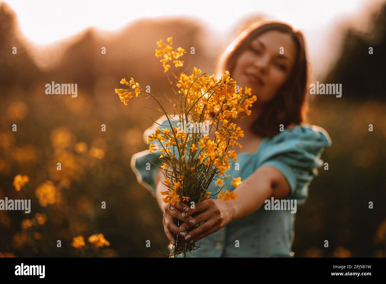 Donna felice in fioritura canola fiori campo. Donna in abito retrò, stagione primaverile Foto Stock