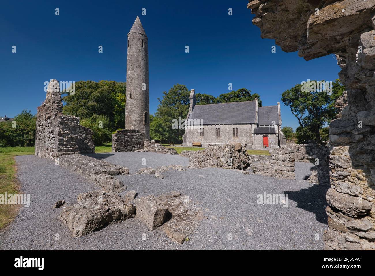 Irlanda, Contea Laois, Timahoe Torre rotonda in parte incorniciata da un muro di una rovina monastica con una chiesa ex Chiesa d'Irlanda che è ora un patrimonio c Foto Stock