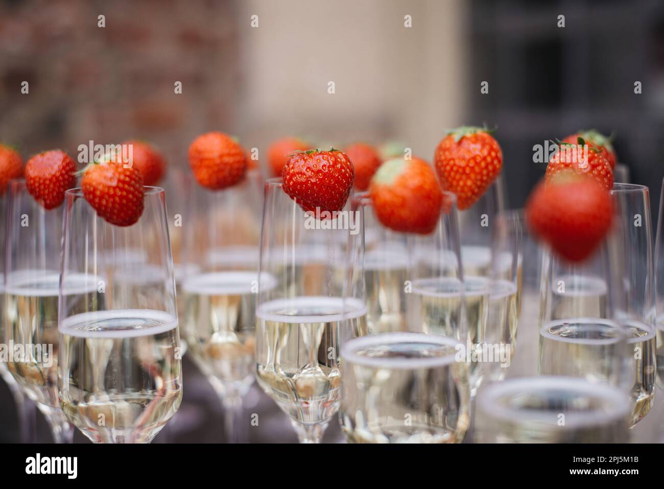 Molti bicchieri di champagne decorati con fragole durante una cerimonia nuziale Foto Stock