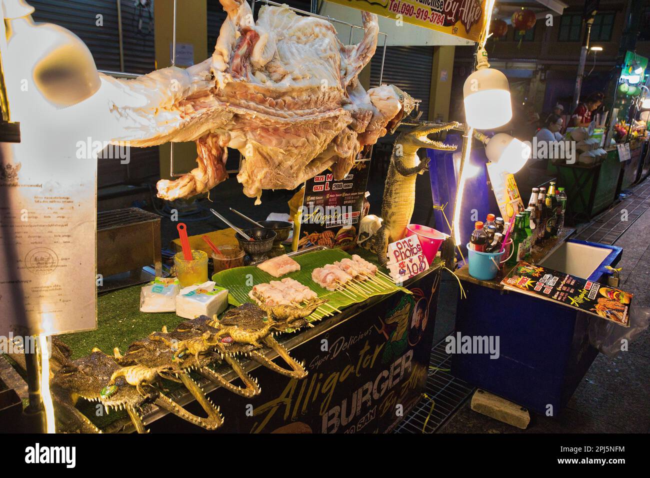 Una bancarella di Street food a Chinatown a Bangkok in Thailandia con un coccodrillo intero che vende carne di coccodrillo. Foto Stock