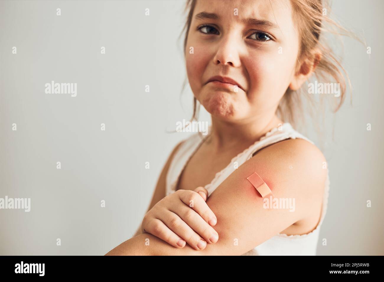 Bambina che sente dolore avendo alcuni effetti collaterali dopo la vaccinazione. Arrossamento, gonfiore, arti doloranti e cefalea come reazione dopo la vaccinazione. Getti Foto Stock