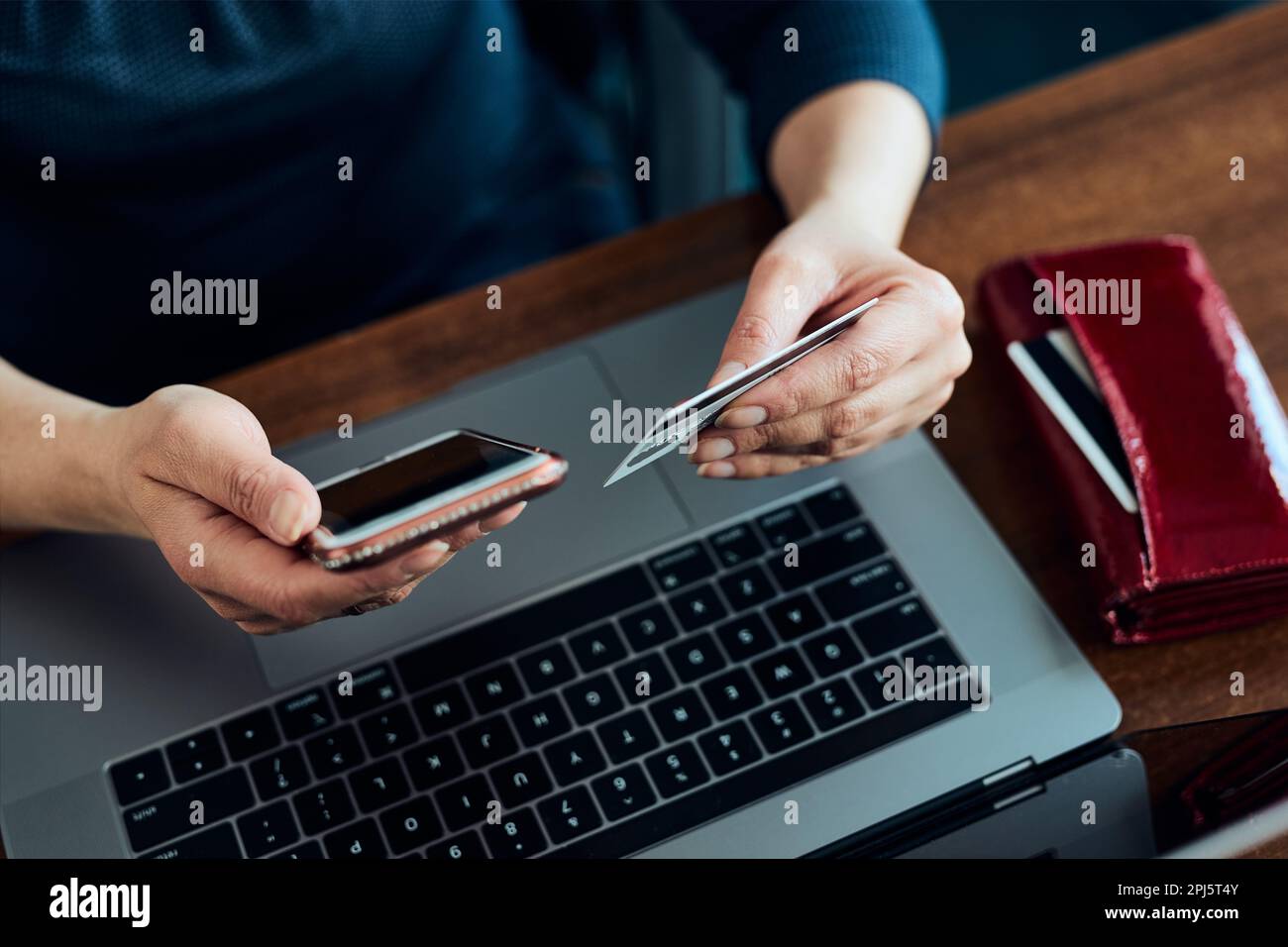 Donna che fa acquisti online con carta di debito e computer portatile. Le mani femminili che tengono la carta di credito sopra una tastiera del laptop seduto ad una scrivania che compra la merce onl Foto Stock