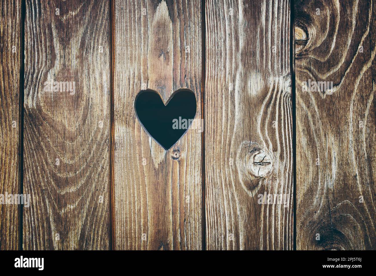 Porta in legno con foro a forma di cuore. Sfondo texture legno. Superficie vecchia tavola rustica Foto Stock