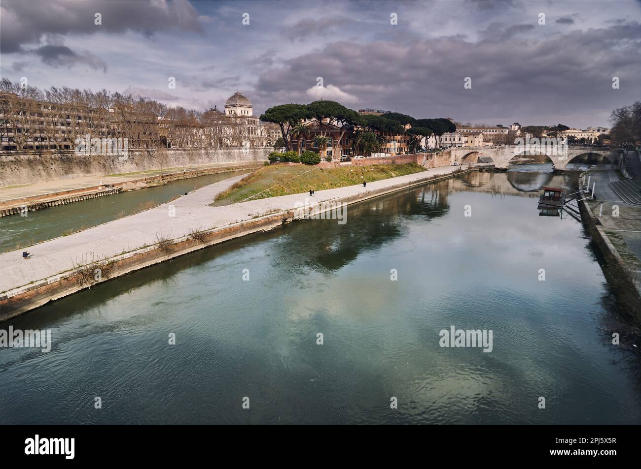 L'isola Tiberina di Roma con rovine di antichi ponti e riflessi sull'acqua Foto Stock