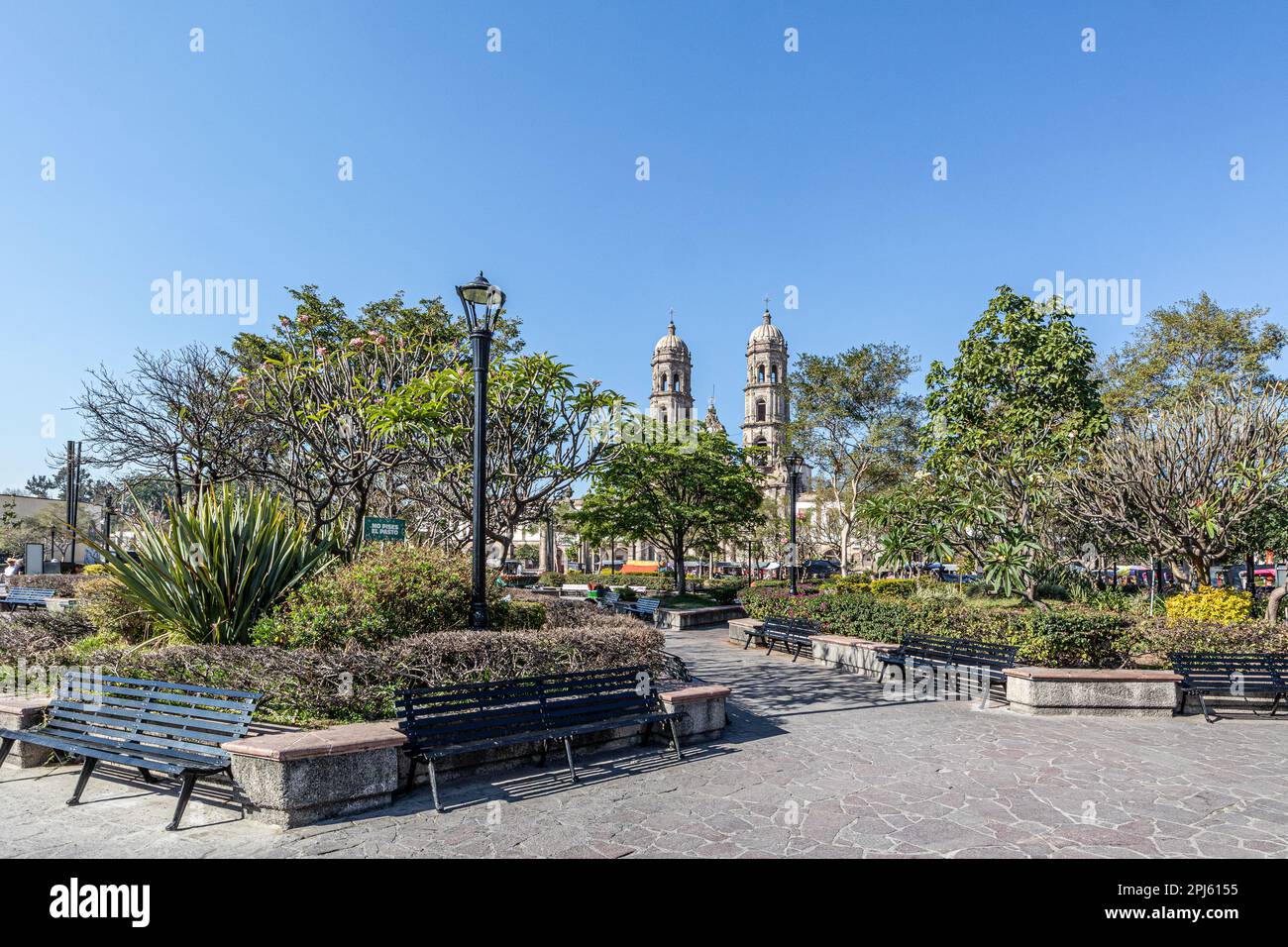 Plaza de las Americas con alberi verdi e sentieri pedonali contro il cielo blu, Basilica di nostra Signora di Zapopan sullo sfondo, segno: Tenere fuori l'erba, Foto Stock