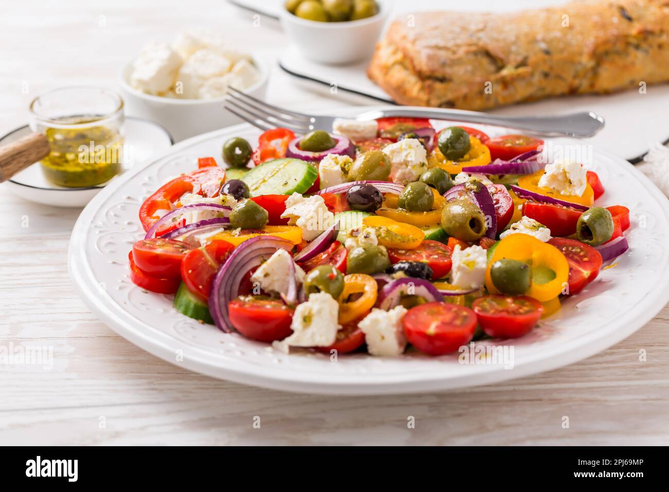 Insalata greca di cetriolo fresco, pomodoro, pepe dolce, lattuga, cipolla rossa, formaggio feta e olive con condimento all'olio d'oliva. Cibo sano Foto Stock