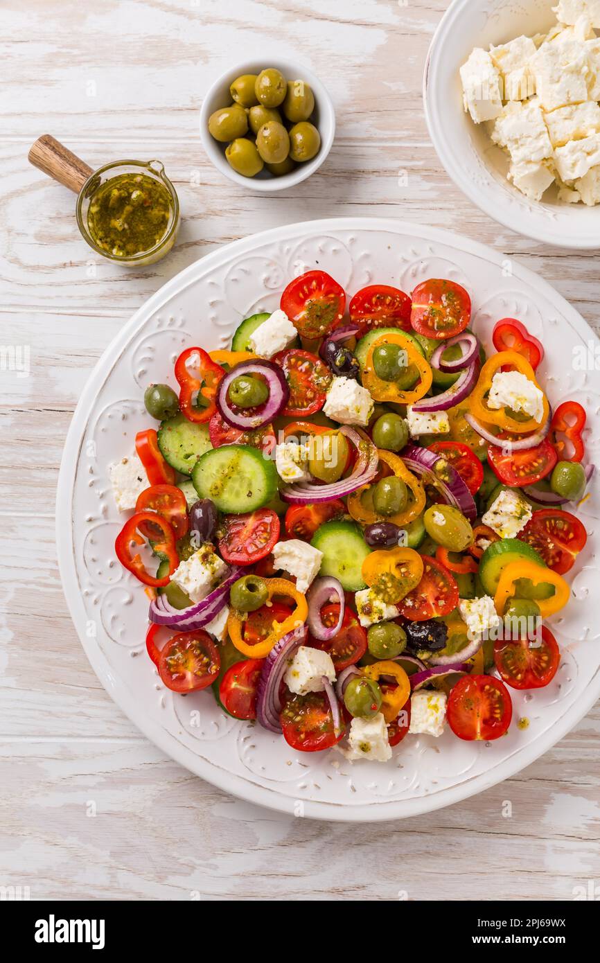 Insalata greca di cetriolo fresco, pomodoro, pepe dolce, lattuga, cipolla rossa, formaggio feta e olive con condimento all'olio d'oliva. Cibo sano, vista dall'alto Foto Stock