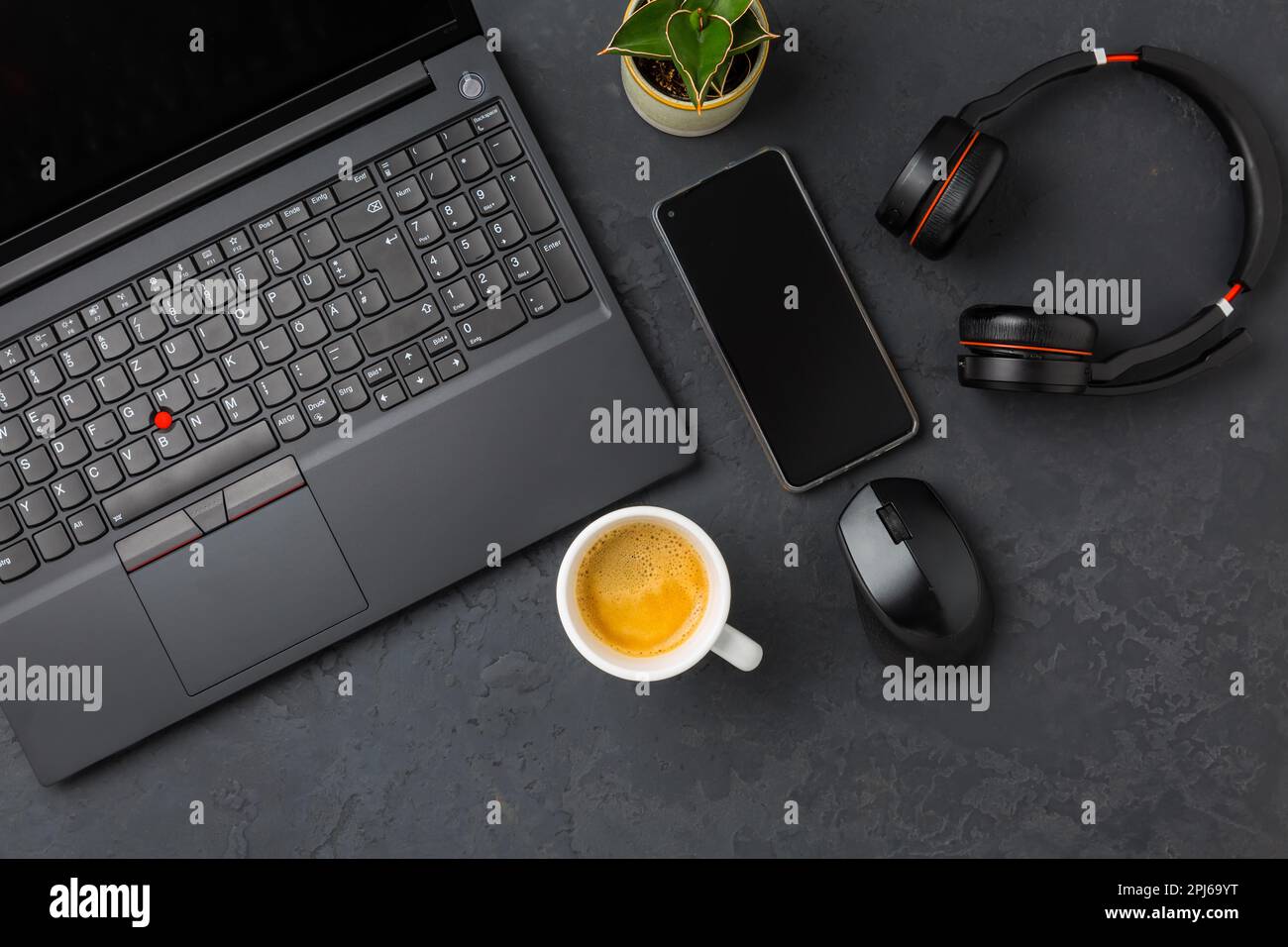 Area di lavoro e scrivania con caffè, computer portatile, cuffie e smarthpone. Piatto in tonalità nera Foto Stock