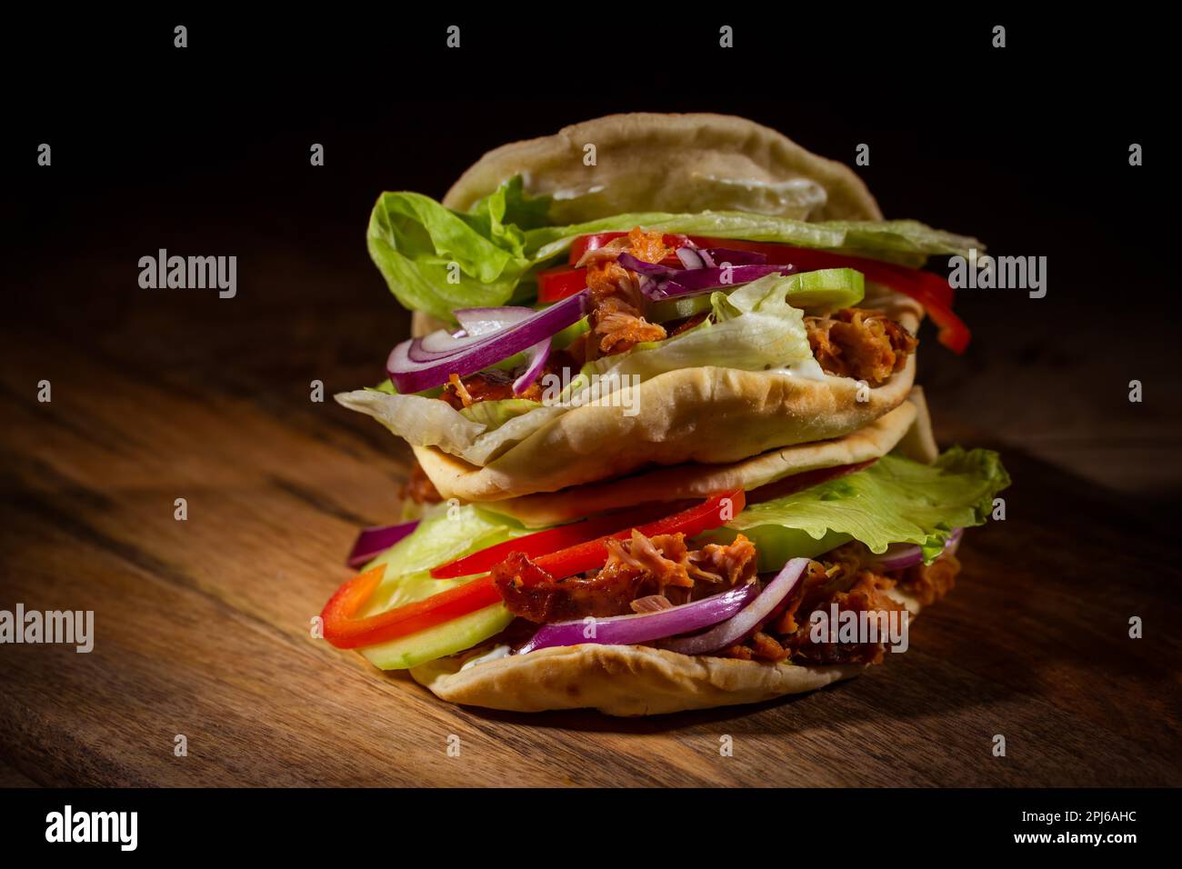 Panino fatto in casa, kebab o doner con carne di pollo, lattuga e verdure su sfondo di legno Foto Stock