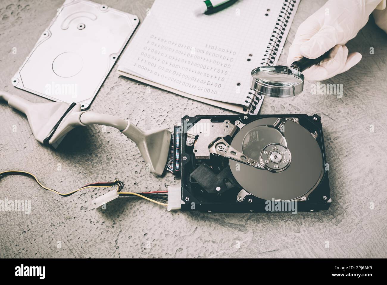 Concetto di recupero dei dati, il tecnico sta recuperando i dati dal driver del disco rigido guasto. Ripristino disco HDD, lente di ingrandimento e codice binario Foto Stock