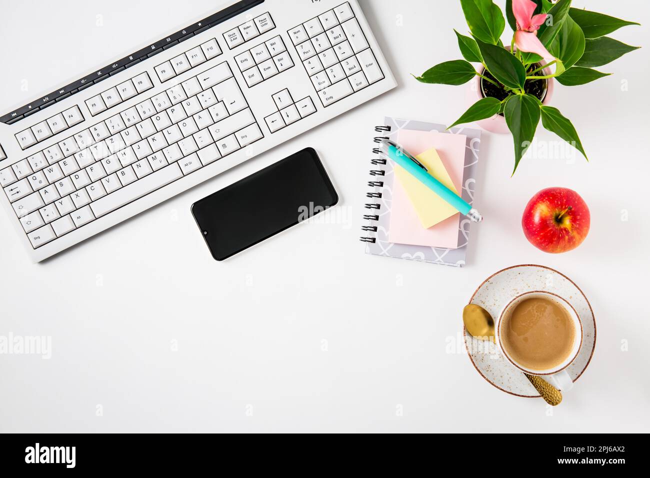 Scrivania da lavoro e ufficio con caffè, mela, computer portatile, cuffie e smarthpone. Piano su sfondo bianco Foto Stock