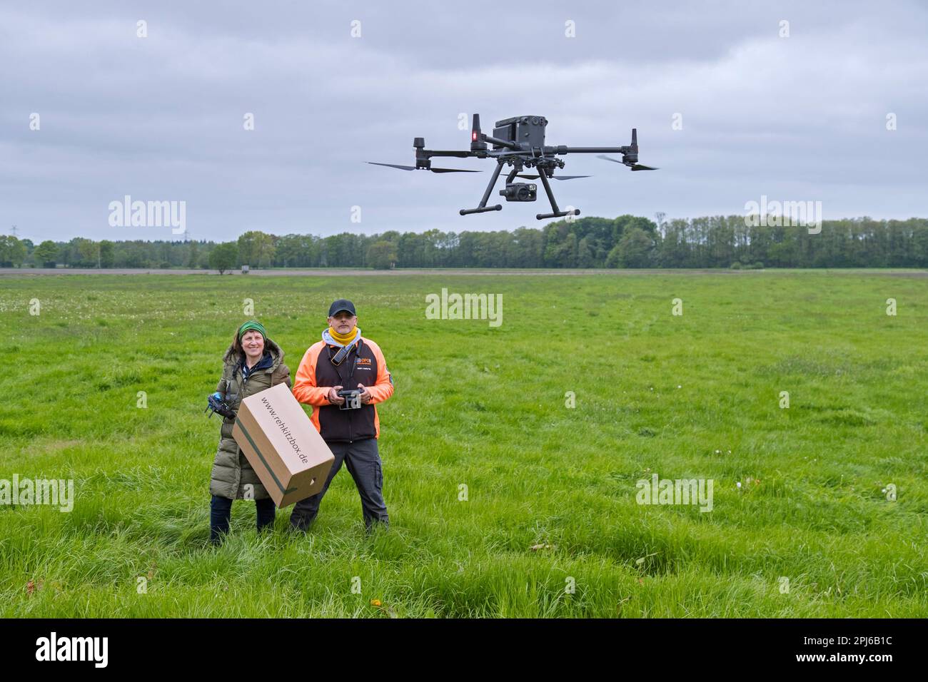 Team di soccorso che gestisce il drone professionale per individuare i caprioli nascosti nell'erba con termocamera prima di tagliare i prati in primavera Foto Stock