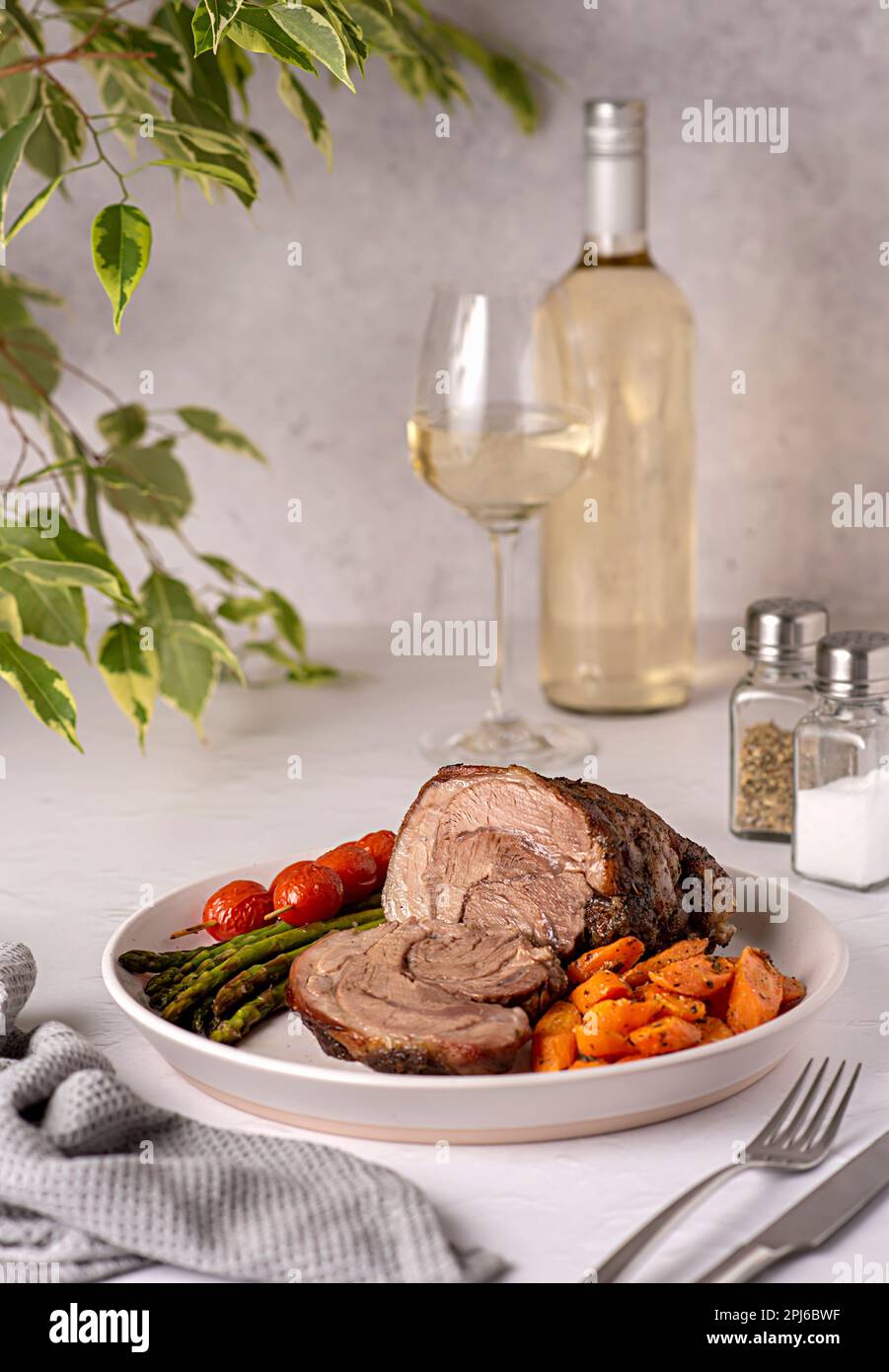 Fotografia alimentare di agnello arrosto, carota, asparagi, pomodoro, vino bianco, bottiglia, wineglass Foto Stock