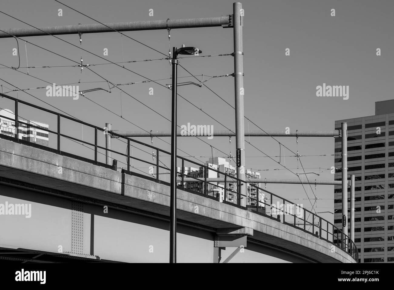 Un tram che attraversa un ponte con un vivace paesaggio urbano sullo sfondo Foto Stock