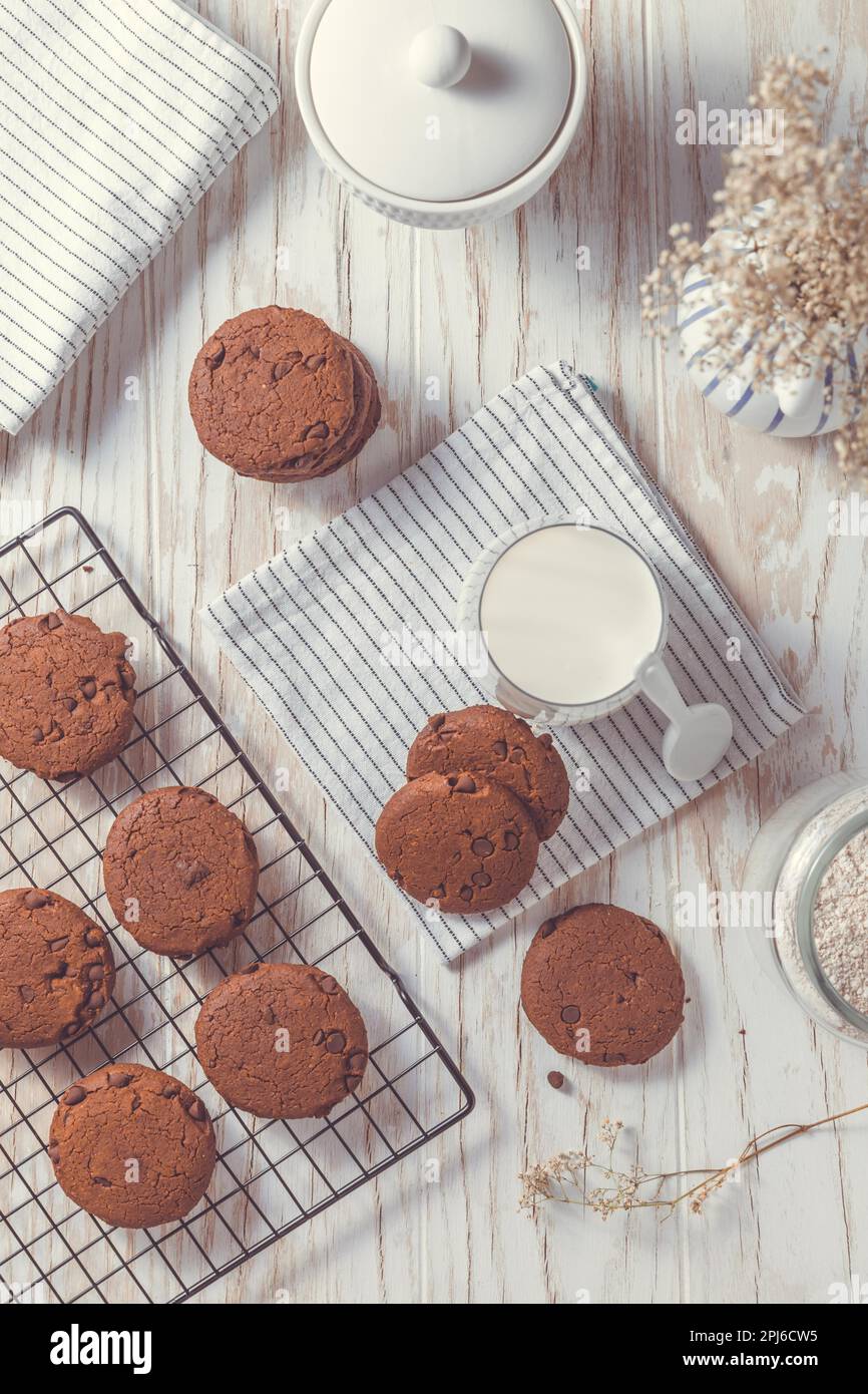 Biscotti al doppio cioccolato con latte sul tavolo da cucina Foto Stock