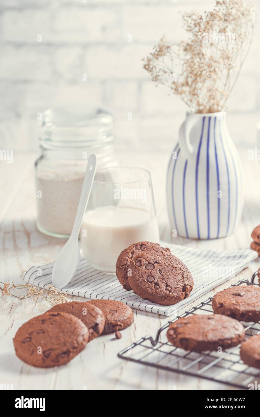 Biscotti al doppio cioccolato con latte sul tavolo da cucina Foto Stock