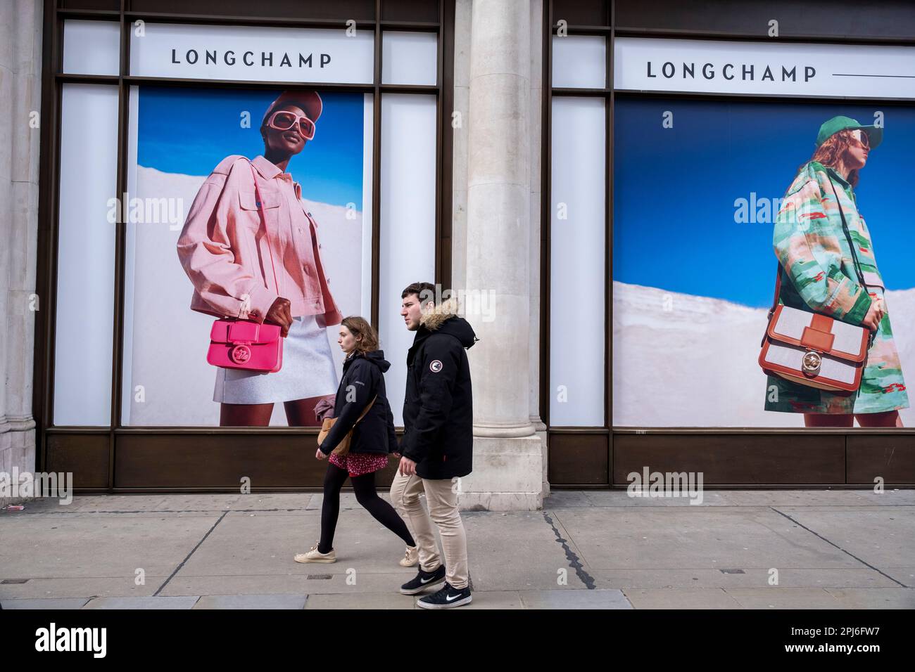 Immagini pubblicitarie su larga scala per il fashion retailer Longchamp il 30th marzo 2023 a Londra, Regno Unito. Le persone che passano interagiscono con le figure di queste fotografie come se fossero piccole in confronto. Longchamp è un'azienda francese di pelletteria, fondata a Parigi nel 1948 da Jean Cassegrain. Questa zona della capitale è nota per i suoi negozi esclusivi i cui vrand sono rivolti ai ricchi e ai ricchi. Foto Stock