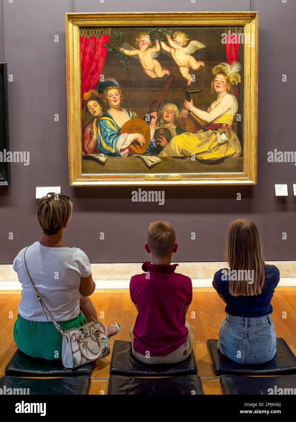 Una donna e due bambini guardano un'immagine su un muro del Louvre, Parigi, Francia, con le spalle al fotografo Foto Stock