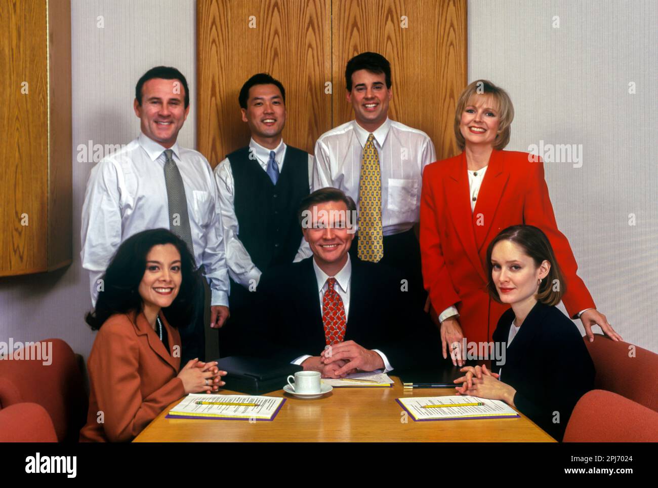 1996 GRUPPO STORICO DI IMPIEGATI CHE SI RIUNISCONO INTORNO AL TAVOLO Foto Stock