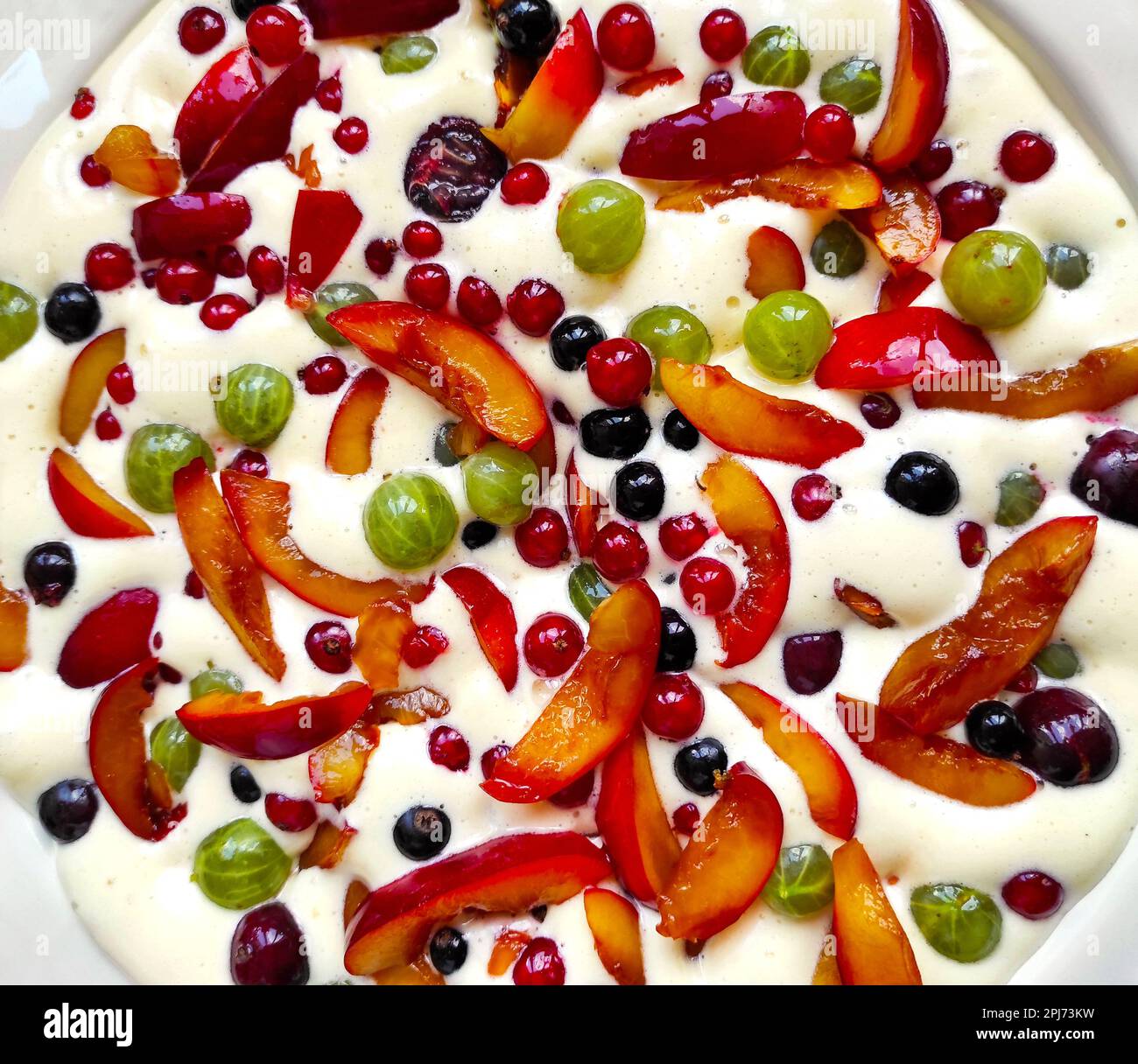 Piatto di clafouti crudo con frutti di bosco e frutta. Vista ravvicinata dall'alto. Torta di clafoutis ai frutti di bosco fatta in casa Foto Stock