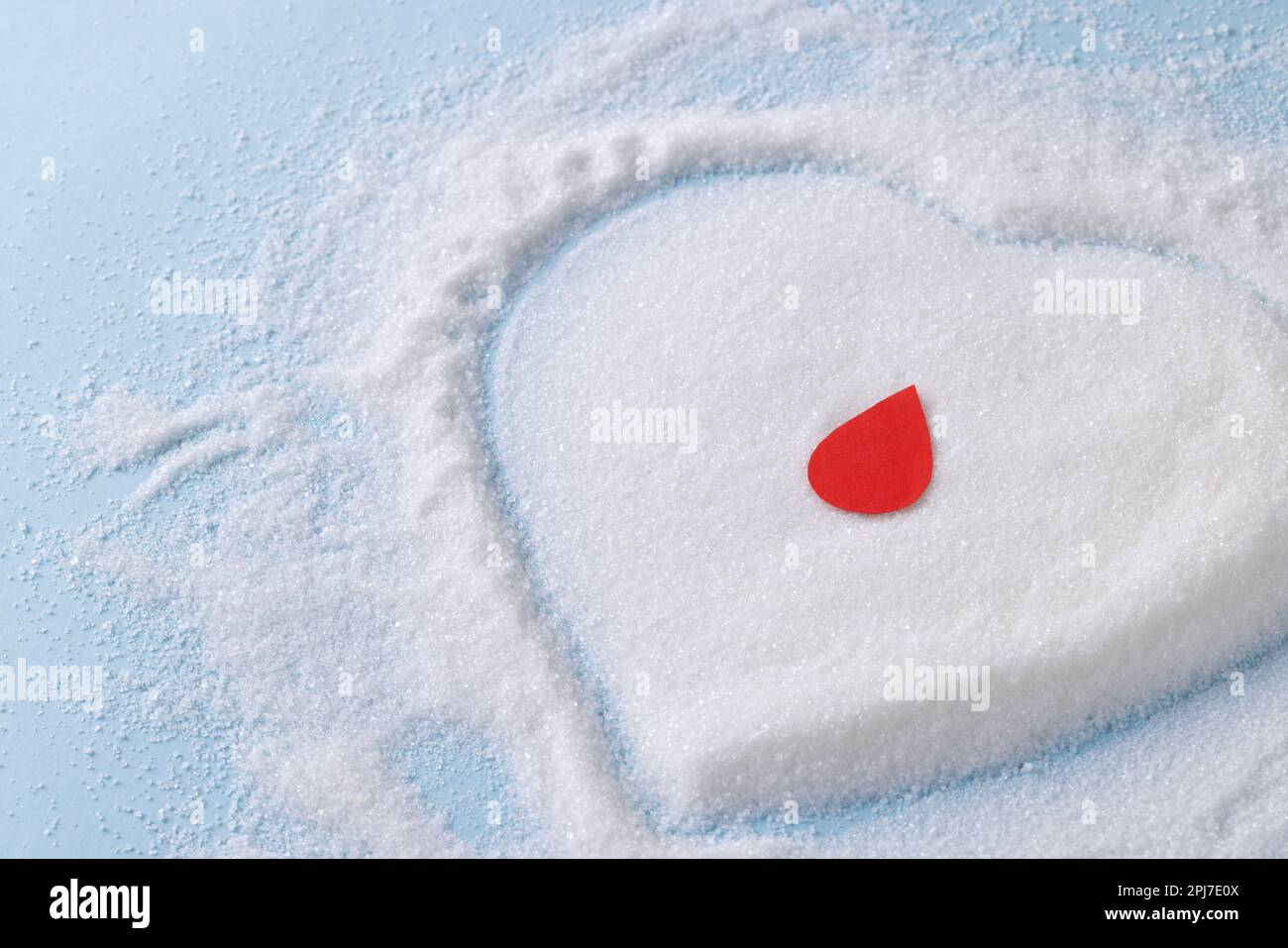 Goccia di sangue sullo zucchero a forma di cuore su sfondo blu Foto Stock