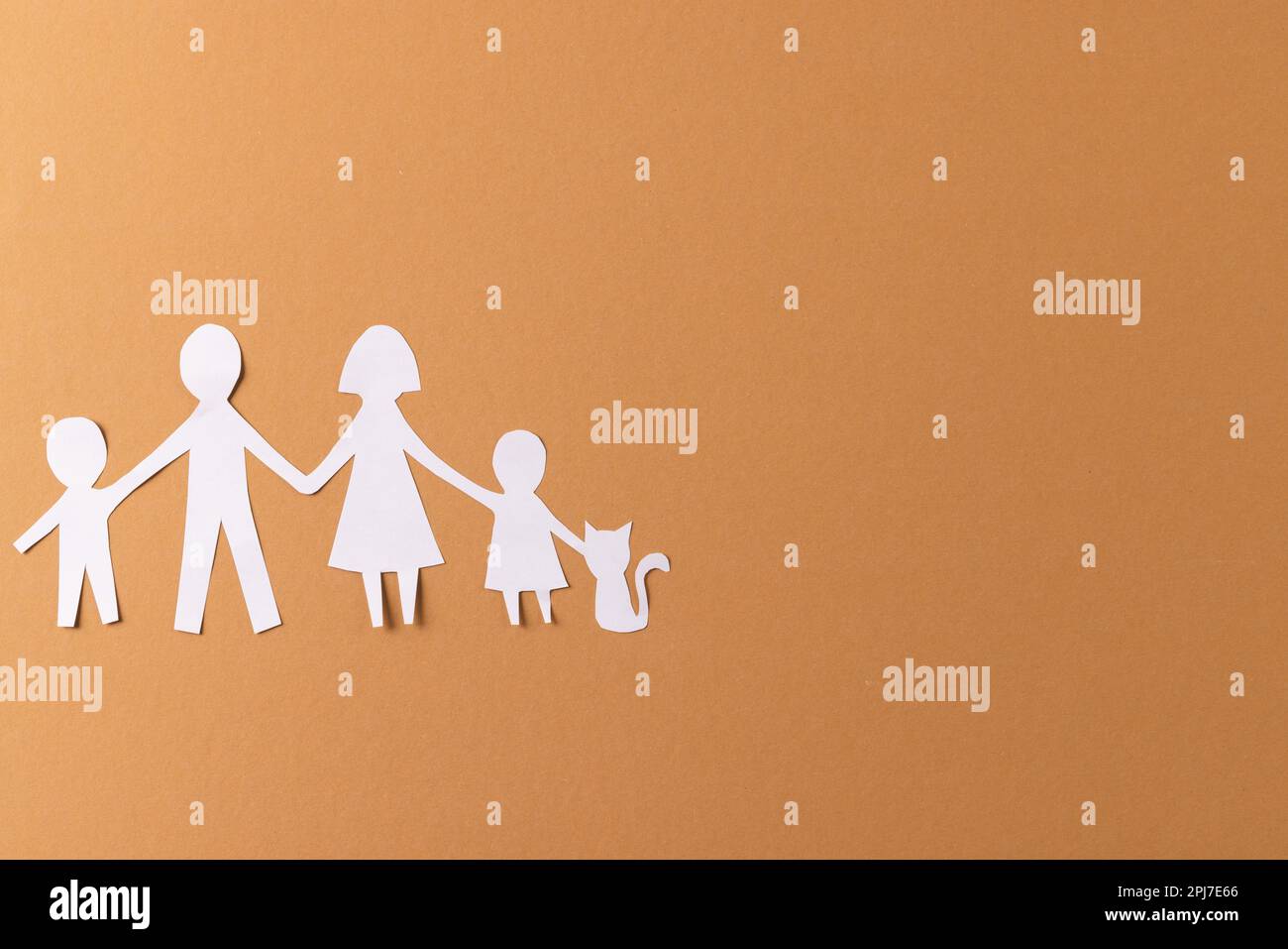 Carta bianca ritagliata dalla famiglia con due bambini e ca e copia spazio su sfondo marrone Foto Stock