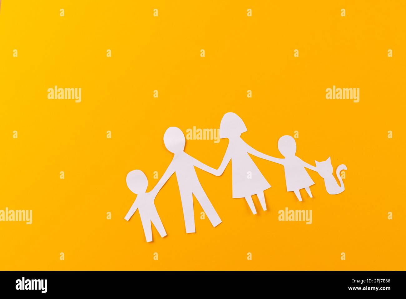 Carta bianca ritagliata dalla famiglia con due bambini e ca e copia spazio su sfondo arancione Foto Stock