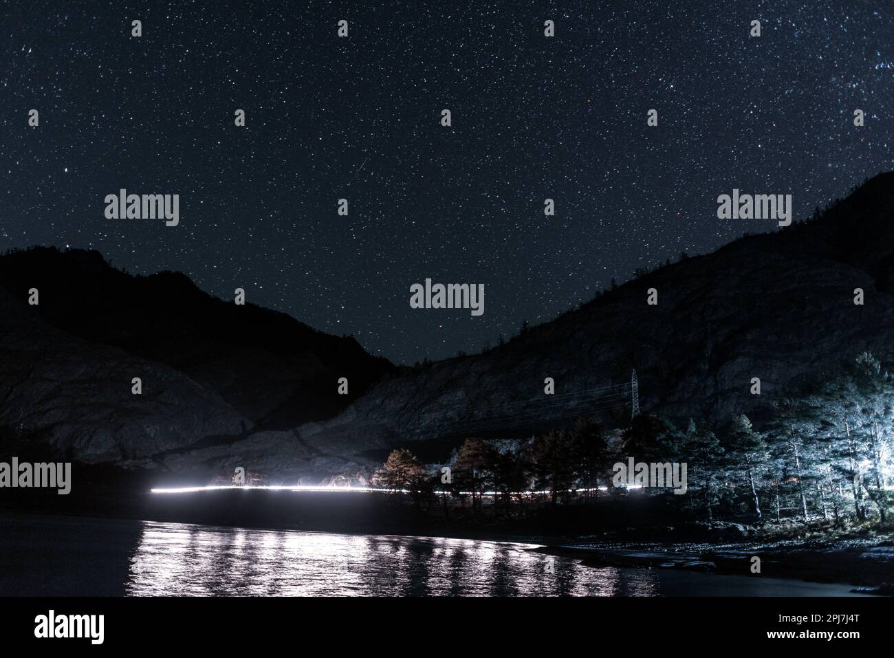 Sentiero leggero dai fari di una macchina di notte su una strada di montagna sotto le stelle vicino a una roccia vicino al fiume Katun in Altai Foto Stock