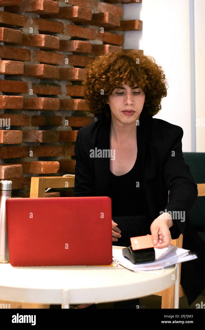 Una persona non binaria sta effettuando un pagamento contactless con una carta di credito Foto Stock