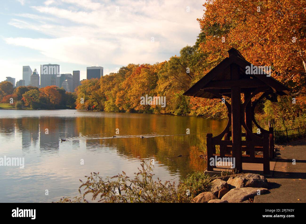 Il fogliame autunnale e lo skyline di New York si riflettono in un lago nel Central Park di New York Foto Stock