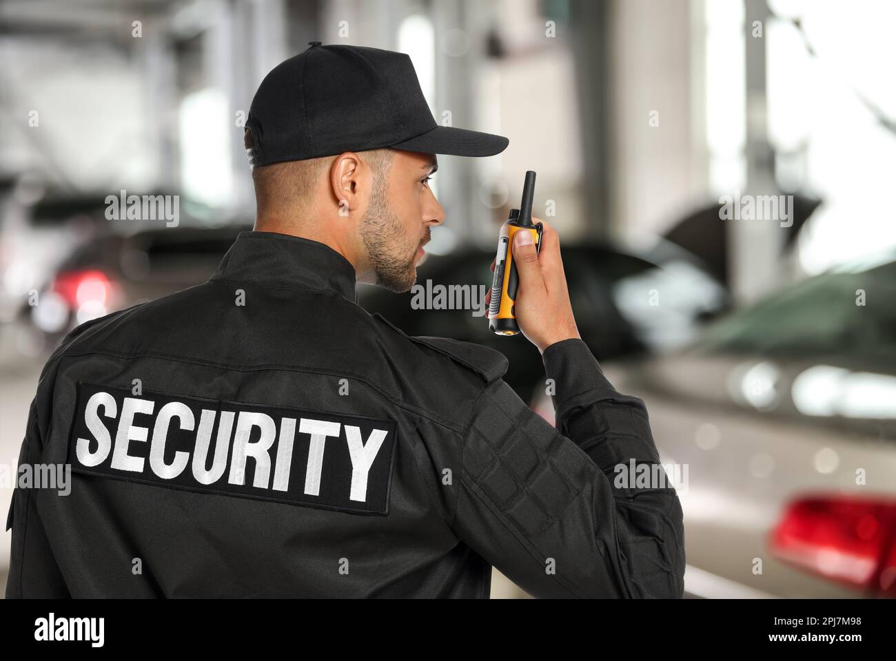 Guardia di sicurezza maschile in uniforme con trasmettitore radio portatile durante il parcheggio Foto Stock