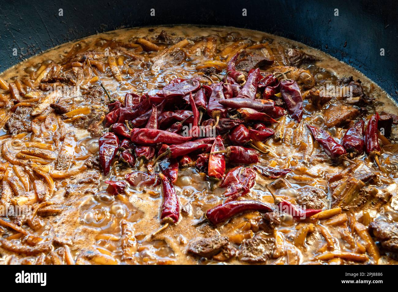 Cialde di pepe rosso caldo in carne bollita con verdure. Una delle fasi di cottura del pilaf uzbeko. Cucina tradizionale nazionale dell'Uzbekistan Foto Stock