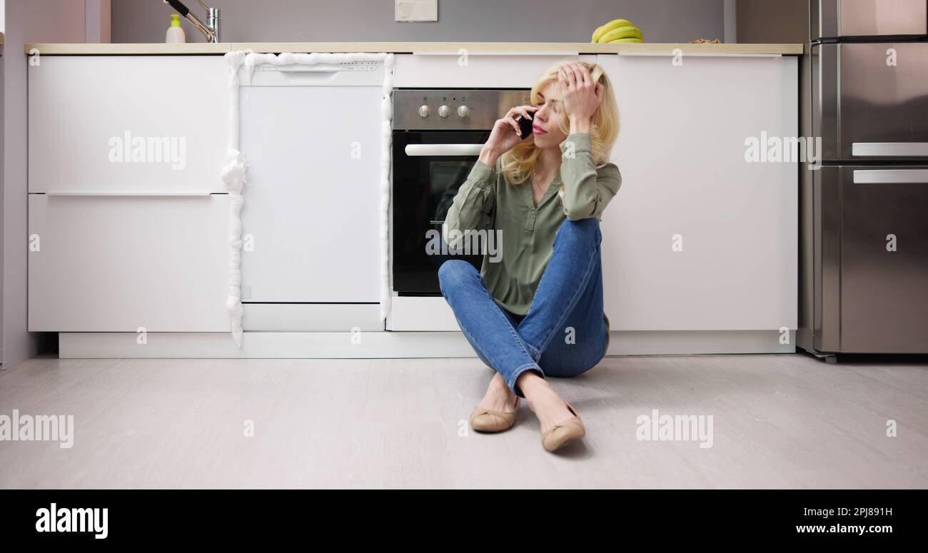 Emergenza apparecchio lavastoviglie rotto. Donna in cucina Foto Stock