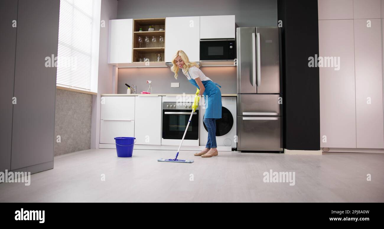 Donna felice pulizia pavimento con Mop in cucina a casa Foto Stock