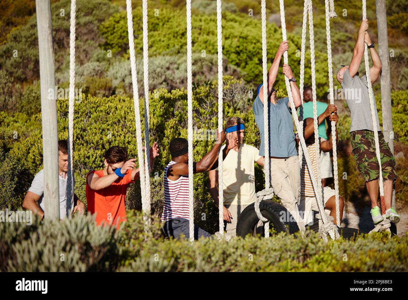La determinazione li porterà alla parte superiore. un gruppo di uomini che si arrampicano sulle corde in un campo militare. Foto Stock
