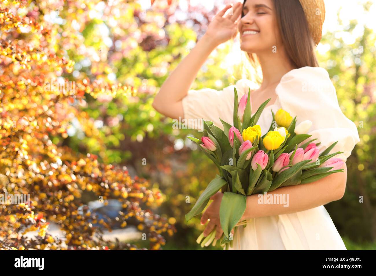 Bella giovane donna con bouquet di tulipani nel parco, focus sui fiori. Spazio per il testo Foto Stock