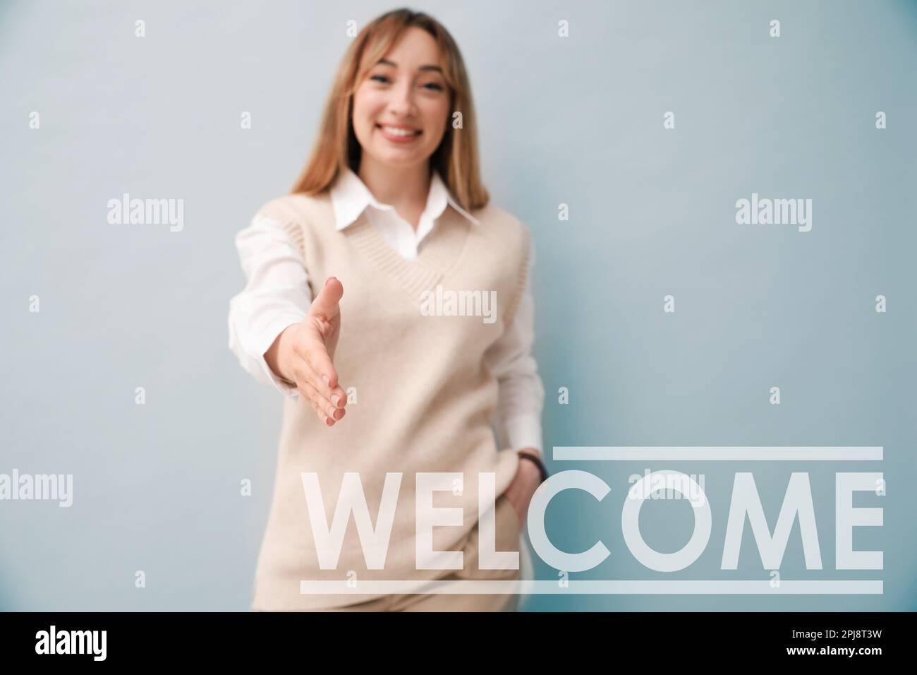 Felice giovane donna che offre handshake su sfondo chiaro, fuoco a portata di mano. Benvenuto nel team Foto Stock